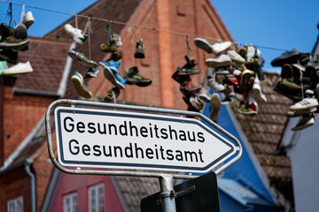 Street sign with arrow to Gesundheitshaus and shoes hanging on overhead wire in flensburg
