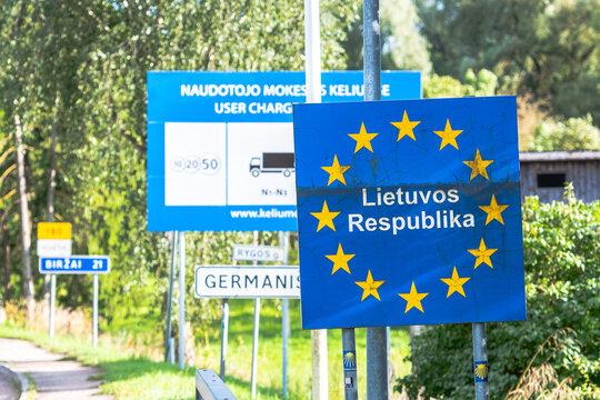 European Union border sign indicating entry into the Republic of Lithuania, Lietuvos Respublika, with the EU circle of stars surrounding the text. The image shows multiple road signs in the background