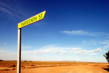 Street sign at a crossing with thirteenth street and an unpaved raod at Orroroo, South Australia.