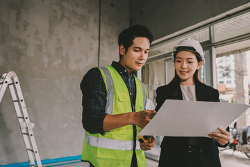 Construction manager and engineer dressed in orange work vests and hard helmets explore...