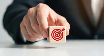 Business professional holding a wooden block with a red bullseye target and arrow symbol signifying success and achievement