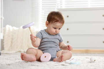 Cute little baby playing with toy pyramid in room
