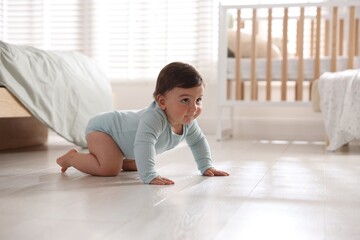 Cute little baby crawling on floor at home, space for text