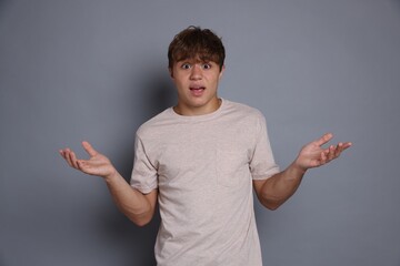 Teenage boy suffering from panic attack on grey background