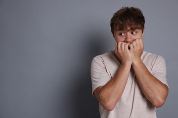 Teenage boy suffering from panic attack on grey background. Space for text