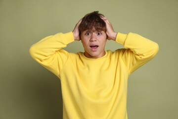 Teenage boy suffering from panic attack on green background