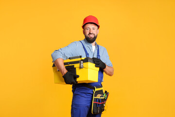 Professional repairman with tool box on orange background