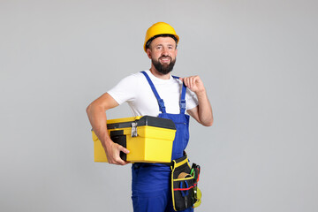 Professional repairman with tool box on grey background