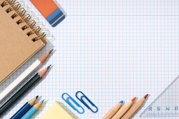 Flat lay of School and office supplies on blank graph paper sheet. Back to school background. Copy...