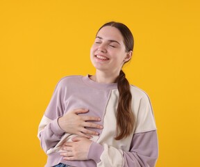 Beautiful woman laughing on yellow background. Positive emotion
