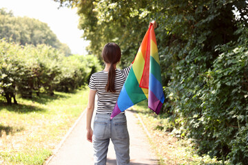 LGBT concept. Woman with rainbow flag outdoors, back view