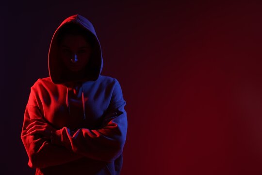 Anonymity. Woman hiding her face on dark red background, space for text