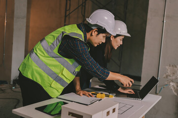 Construction manager and engineer dressed in orange work vests and hard helmets explore...