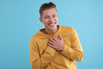 Handsome man laughing on light blue background. Positive emotion