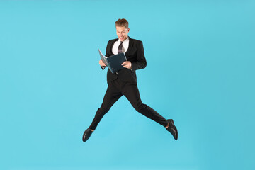 Fototapeta premium Businessman with folder jumping on light blue background