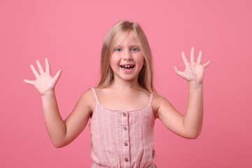 Cute little girl laughing on pink background