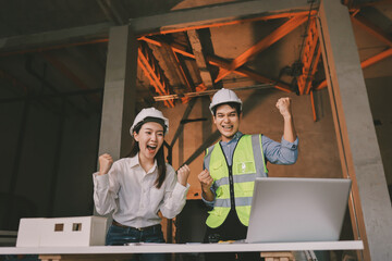 Construction manager and engineer dressed in orange work vests and hard helmets explore...
