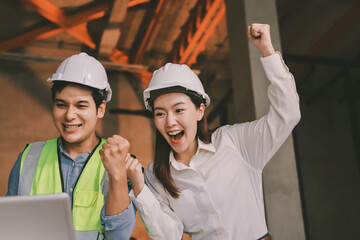 Construction manager and engineer dressed in orange work vests and hard helmets explore...