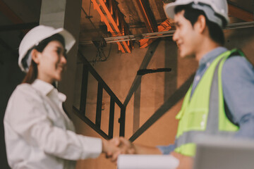 Construction manager and engineer dressed in orange work vests and hard helmets explore...
