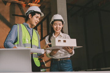 Construction manager and engineer dressed in orange work vests and hard helmets explore...