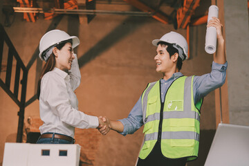 Construction manager and engineer dressed in orange work vests and hard helmets explore...