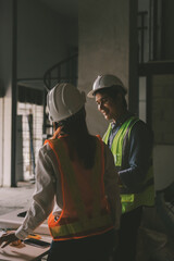 Construction manager and engineer dressed in orange work vests and hard helmets explore...