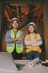 Construction manager and engineer dressed in orange work vests and hard helmets explore...