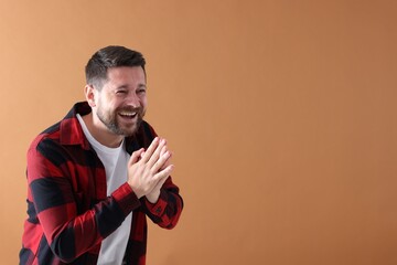 Handsome man laughing on dark beige background, space for text