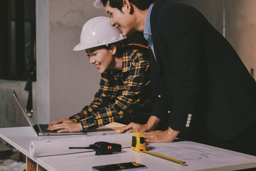 Construction manager and engineer dressed in orange work vests and hard helmets explore...