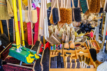 Variety of cleaning tools displayed at a market stall during daylight, showcasing different brushes...