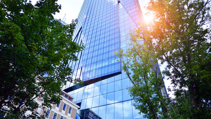 Sustainable glass office building with trees for reducing carbon dioxide. Eco-friendly building in modern city. Office with green environment. Corporate building reduce CO2.