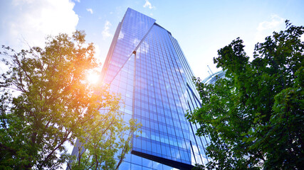 Sustainable glass office building with trees for reducing carbon dioxide. Eco-friendly building in...