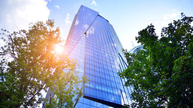 Sustainable glass office building with trees for reducing carbon dioxide. Eco-friendly building in modern city. Office with green environment. Corporate building reduce CO2.