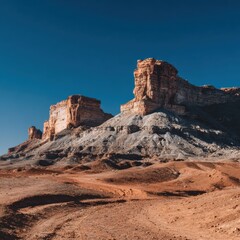 Fototapeta premium Dramatic Desert Landscape Featuring Rocky Outcrops Under Clear Blue Sky with Striking Shadows and Unique Terrain