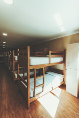 Spacious hostel dormitory interior with multiple wooden bunk beds, clean white bedding, lockers and...