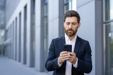 Businessman using smartphone outside modern office building in the city