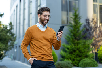 Smiling man using smartphone outdoors in urban setting