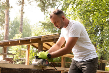 Carpenter works with electric plane on wooden board. Craftsman runs his own successful small...