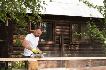 Carpenter works with electric plane on wooden board. Craftsman runs his own successful small...