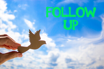 Follow up symbol. Concept word Follow up on beautiful blue sky. Businessman's hand with wooden...