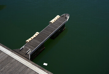 Wooden dock with floating cushions on calm green water, ideal for relaxation and leisure activities