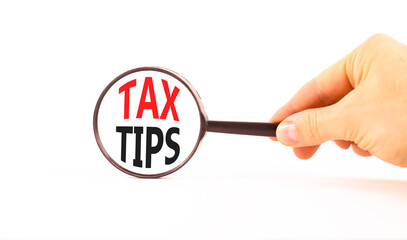 Tax tips symbol. Concept word Tax tips on beautiful magnifying glass. Businessman's hand. Beautiful...