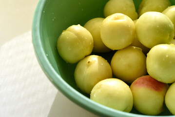 A ripe yellow plum in a green basin. Juicy fruit. Ripe plums in drops of water.
