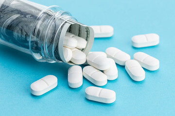 Medicine cost concept. US Dollars and medicine pills spilling from medicine bottle