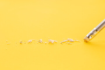 Pencil eraser working on yellow paper background. Mistake, erasing or correction concept. Copy space