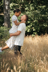 Fototapeta premium Romantic diverse couple embracing in nature, enjoying summer together, lifestyle and love concept, authentic outdoor moment.