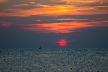 Sailing boat silhoutted against the orange sky