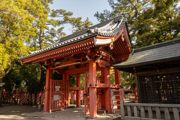 Naklejka premium A vibrant red torii gate with traditional Japanese architecture at Sumiyoshi Taisha in Osaka, Japan. Its an entrance to a Shinto shrine, showcasing intricate carvings and a rich history.