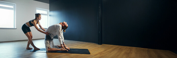 Yoga Instructor Assisting Pose in Wide Banner