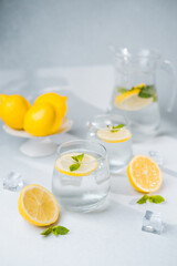 Lemon water with mint and ice in glasses and jug